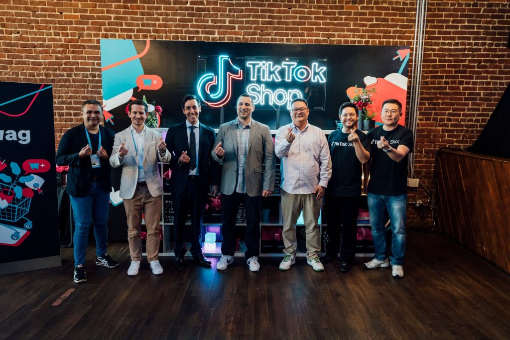 A group photo of attendees at the TikTok Shop event, posing in front of the neon TikTok Shop sign. The guests showcase a sense of community and excitement.