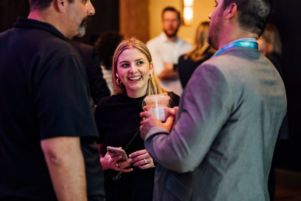 A woman in a black outfit engaged in conversation with other attendees at the TikTok Shop event. The setting encourages networking and socializing.