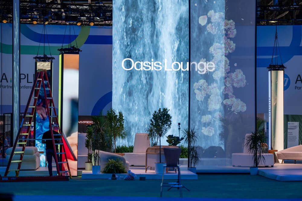 The Oasis Lounge area being prepared at the HP Amplify Partner Conference 2024 featuring a waterfall display and plants