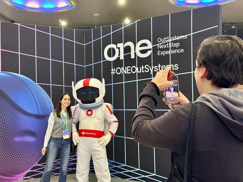 Person posing with a mascot at OutSystems event