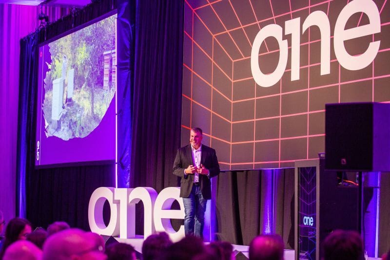 Speaker presenting on stage with one branding